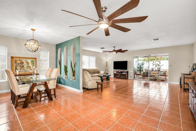 tiled dining room featuring ceiling fan with notable chandelier