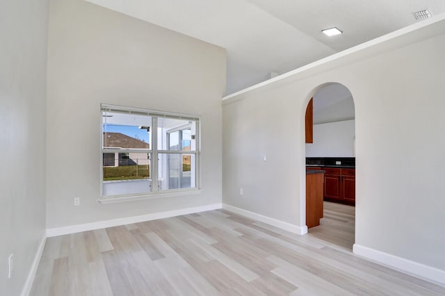 unfurnished room with lofted ceiling and light hardwood / wood-style flooring