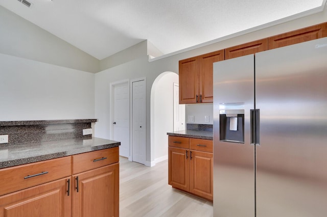 kitchen featuring light hardwood / wood-style flooring, lofted ceiling, and stainless steel refrigerator with ice dispenser