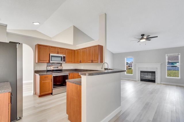 kitchen featuring appliances with stainless steel finishes, ceiling fan, light wood-type flooring, and kitchen peninsula