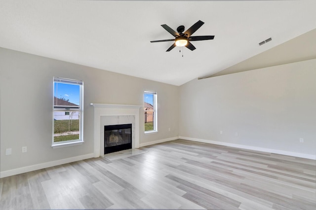 unfurnished living room featuring light wood-type flooring, a high end fireplace, and plenty of natural light