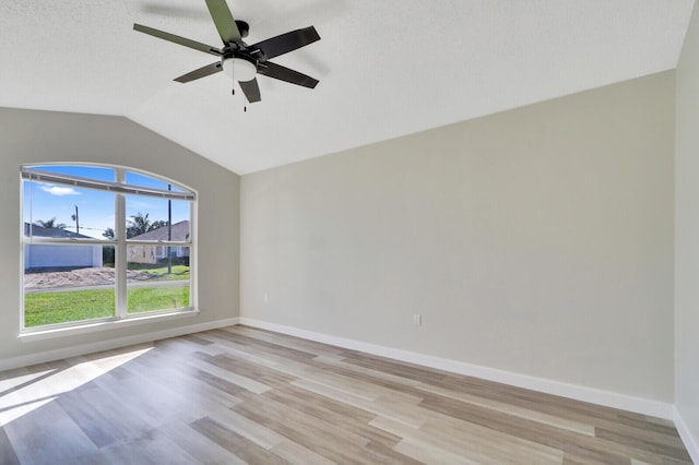 spare room with light wood-type flooring, ceiling fan, vaulted ceiling, and a textured ceiling