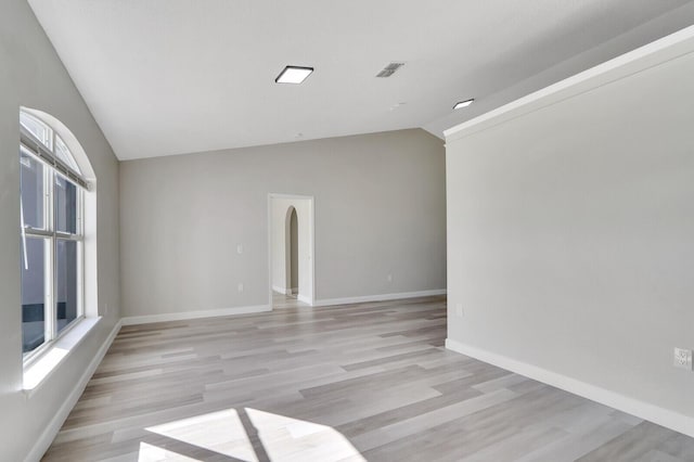 spare room with lofted ceiling and light wood-type flooring