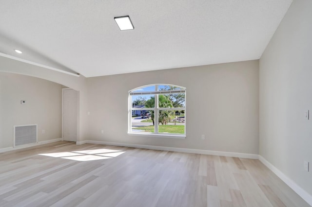 unfurnished room with light wood-type flooring and a textured ceiling