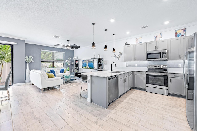 kitchen featuring stainless steel appliances, sink, decorative light fixtures, kitchen peninsula, and gray cabinetry