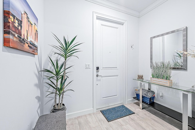 foyer entrance with ornamental molding and light hardwood / wood-style floors