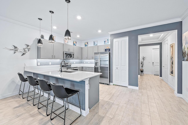 kitchen with sink, kitchen peninsula, hanging light fixtures, gray cabinetry, and appliances with stainless steel finishes