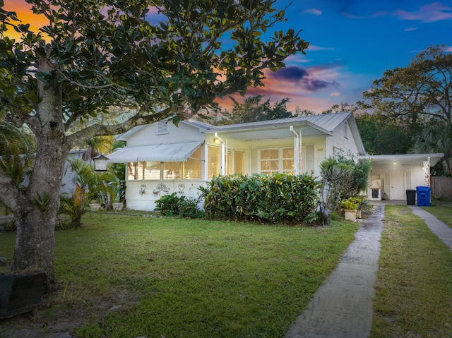 property exterior at dusk featuring a yard and a carport