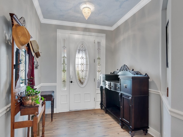 entrance foyer with ornamental molding and light hardwood / wood-style flooring