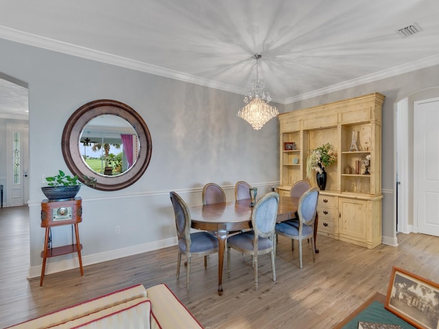 dining space with an inviting chandelier, ornamental molding, and hardwood / wood-style flooring