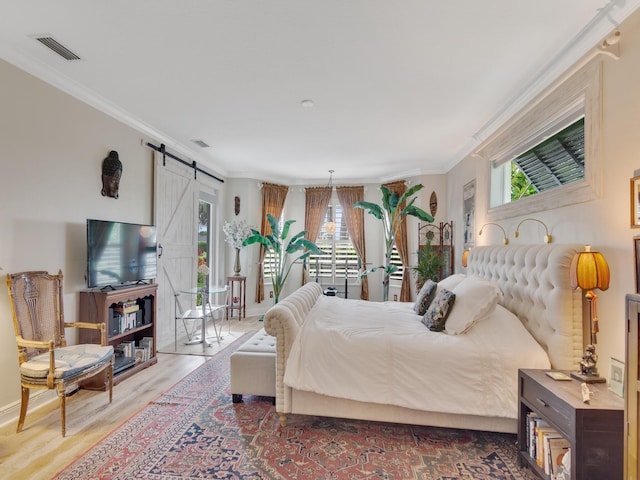 bedroom featuring ornamental molding, a barn door, and wood-type flooring