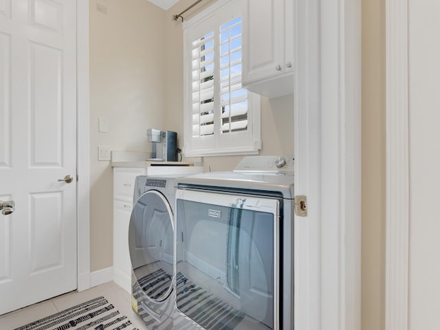 laundry area featuring washer and dryer, light tile patterned floors, and cabinets