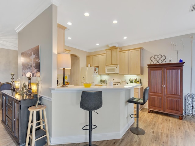 kitchen featuring a breakfast bar area, white appliances, crown molding, and kitchen peninsula