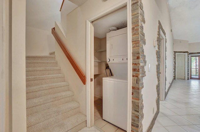 laundry area featuring light tile patterned flooring and stacked washer and clothes dryer