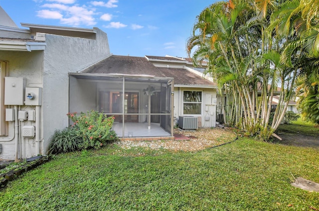 back of house with central AC unit, a yard, and a sunroom