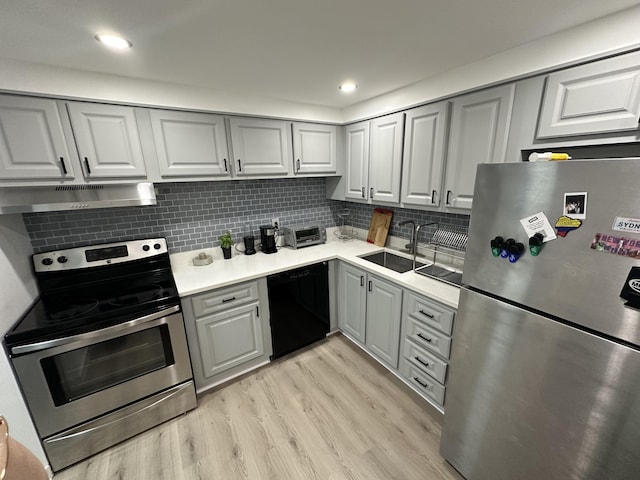 kitchen with sink, backsplash, light wood-type flooring, gray cabinetry, and stainless steel appliances