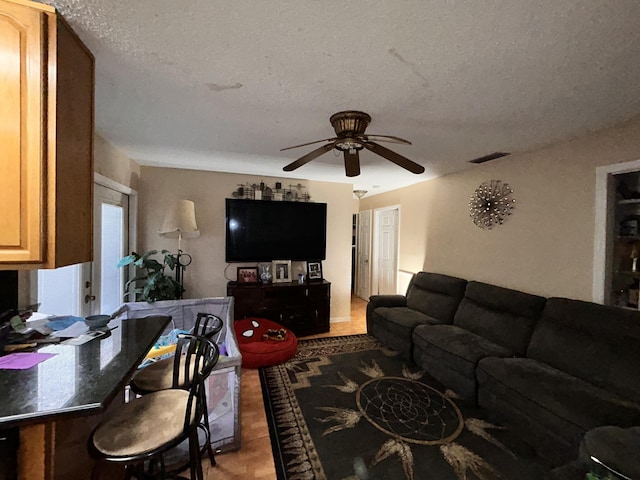 living room with a textured ceiling and ceiling fan