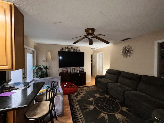 tiled living room with a textured ceiling and ceiling fan