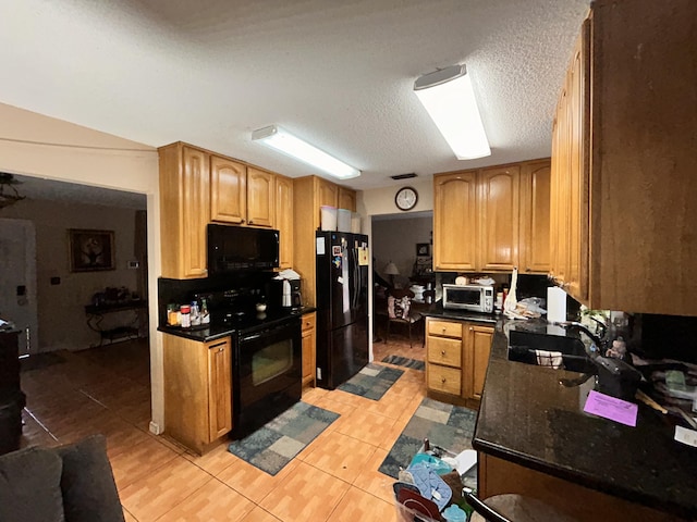 kitchen with sink, light tile patterned flooring, a textured ceiling, and black appliances