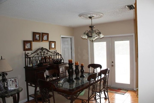 dining space featuring a textured ceiling, french doors, light tile patterned floors, and a chandelier