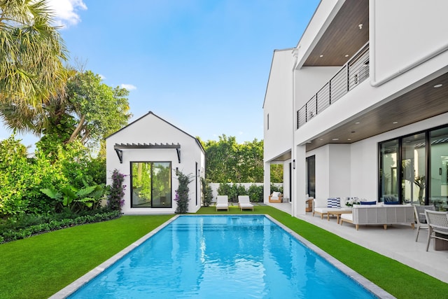 view of swimming pool featuring a patio, an outdoor hangout area, an outbuilding, and a yard