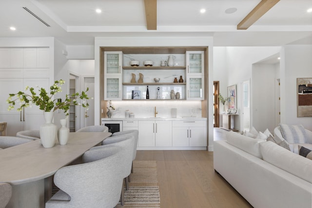 interior space with bar, beam ceiling, light hardwood / wood-style floors, and beverage cooler