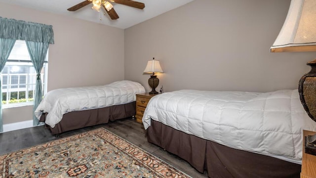 bedroom with ceiling fan, multiple windows, and dark hardwood / wood-style flooring