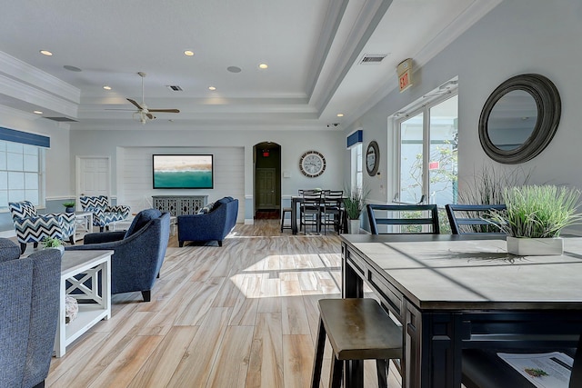 dining space featuring ceiling fan, a tray ceiling, crown molding, and light wood-type flooring