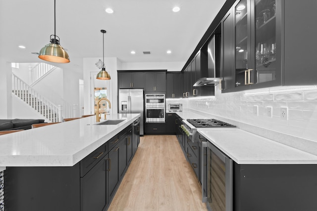 kitchen featuring sink, hanging light fixtures, stainless steel appliances, wine cooler, and wall chimney exhaust hood