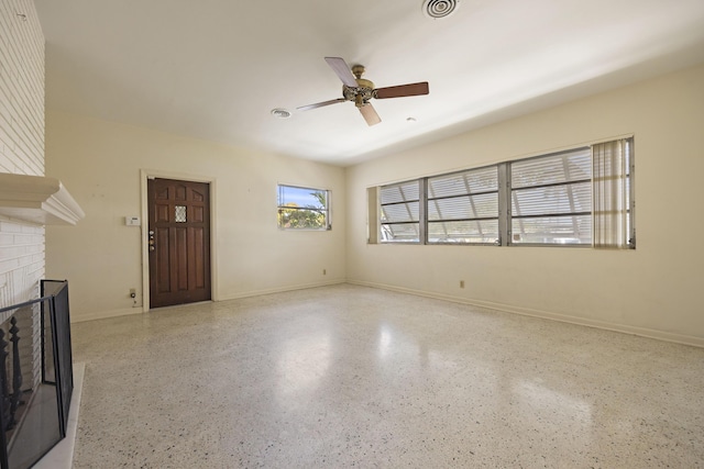 unfurnished living room featuring ceiling fan and a fireplace