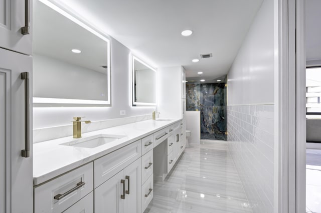 bathroom featuring toilet, tile walls, a shower with shower door, and vanity