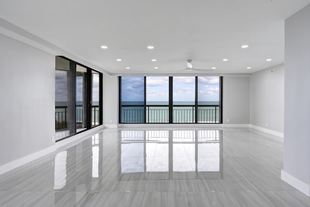 unfurnished room with a wall of windows, a water view, and light tile patterned flooring