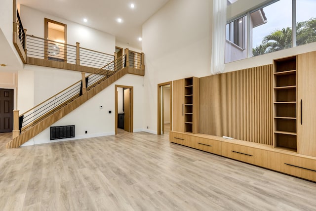 unfurnished living room with a high ceiling and hardwood / wood-style flooring