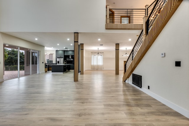 unfurnished living room featuring an inviting chandelier and light hardwood / wood-style floors