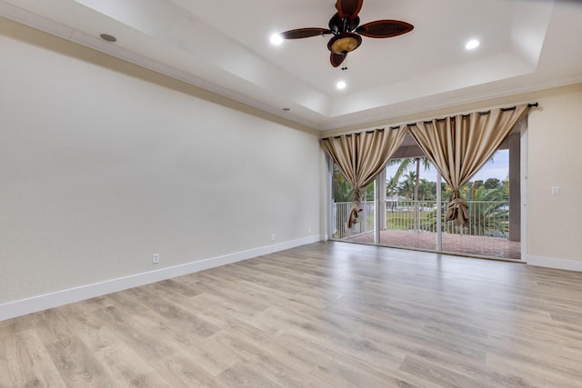 empty room featuring ceiling fan, ornamental molding, light hardwood / wood-style flooring, and a tray ceiling