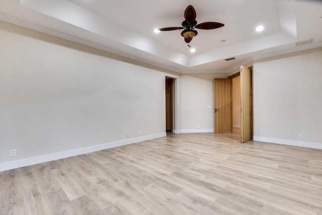 interior space with ceiling fan, light hardwood / wood-style floors, a tray ceiling, and crown molding