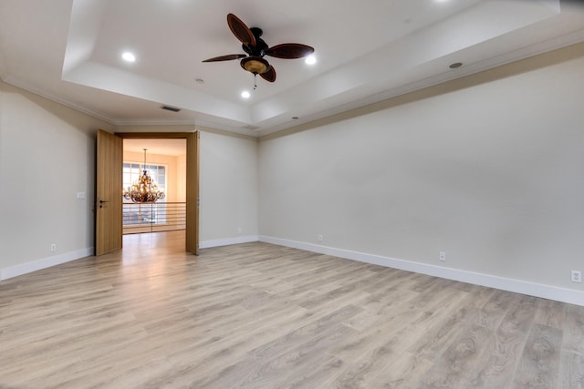 spare room with a raised ceiling, ceiling fan with notable chandelier, ornamental molding, and light hardwood / wood-style flooring