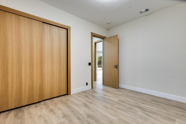 unfurnished bedroom with a closet and light hardwood / wood-style floors