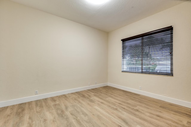 unfurnished room with light wood-type flooring and a textured ceiling