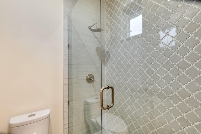 bathroom with a shower with shower door and toilet