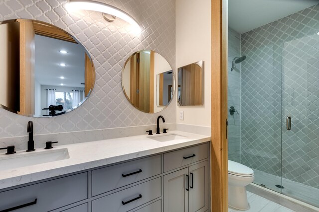 bathroom featuring a shower with shower door, toilet, and vanity