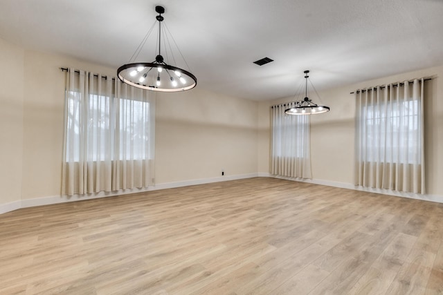 unfurnished dining area with light hardwood / wood-style floors and an inviting chandelier