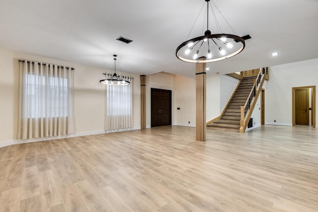 unfurnished living room with light hardwood / wood-style flooring and a chandelier