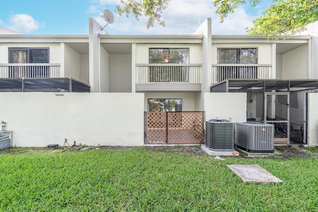 rear view of property featuring a balcony, cooling unit, and a lawn