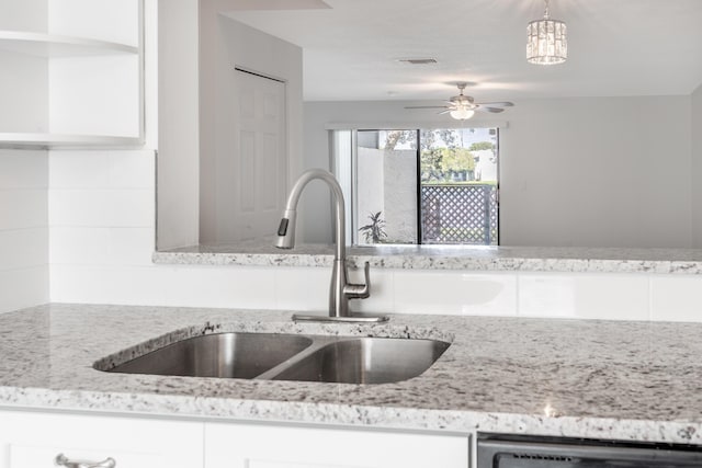 kitchen with sink, white cabinets, light stone counters, ceiling fan, and hanging light fixtures