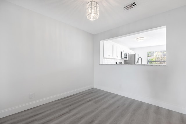 spare room featuring a notable chandelier, sink, and wood-type flooring