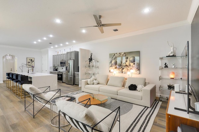 living room featuring ceiling fan, light hardwood / wood-style flooring, crown molding, and sink