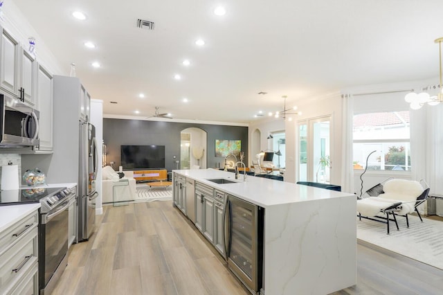 kitchen featuring decorative light fixtures, stainless steel appliances, wine cooler, crown molding, and sink