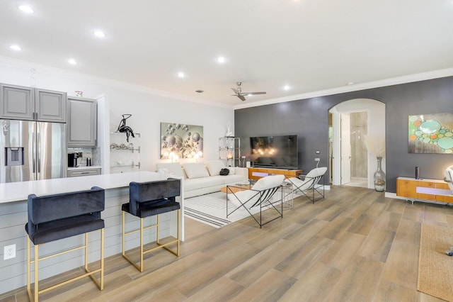 living room featuring ceiling fan, ornamental molding, and light hardwood / wood-style flooring