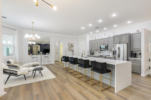 kitchen featuring a breakfast bar, appliances with stainless steel finishes, gray cabinets, and a spacious island